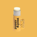 A Poppy & Pout Lip Balm tube with the cap off reveals the product inside, displayed against a solid yellow background.