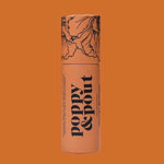 An orange cylindrical tube labeled "Poppy & Pout" with floral art sits on a matching background—highlighting the handmade, natural Lip Balm by Poppy & Pout.