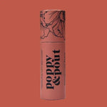 The Poppy & Pout Lip Balm features a beautifully designed cylindrical tube with floral illustrations on a coral background, offering a cruelty-free and natural lip care solution.