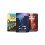 Three Field Notes National Parks Pack memo books with illustrated covers, including a Graph Paper Notebook, stand upright against a white background.