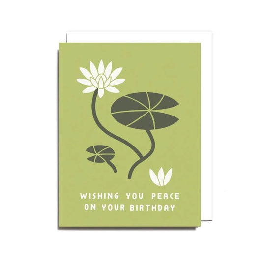 The Peace on Your Birthday Card by Worthwhile Paper features white lotus blossoms and lily pads with "Wishing you peace on your birthday" at the bottom. Printed on recycled card stock for an eco-friendly touch.