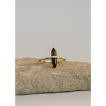 The JaxKelly Smokey Quartz Point Ring features a double-terminated dark crystal set in 14kt gold vermeil, shown on a light stone surface against a plain background.