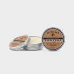 Two round tins of Otter Wax Saddle Soap by Otter Wax, one open to reveal the soap and one closed, both featuring brown labels, displayed on a plain white background.