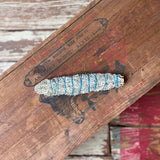 The Smudge Stick | Grandfather by Taos Herb Co. is wrapped with blue string and displayed on a vintage wooden box with faded labels and visible wood grain.