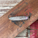 A Taos Herb Co. Smudge Stick | Seven Direction, wrapped with string, sits atop a weathered wooden surface marked by faded red and black lettering.