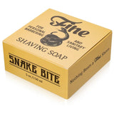 A yellow box of Fine Accoutrements' Snake Bite Shaving Soap features a coiled snake logo, promotes personal barbering and sanitary living, and highlights its intensely mentholated cooling effect.