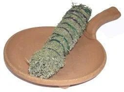A bundle of dried sage tied with string rests on a round, handled Terracotta Smudging Bowl by Taos Herb Co., handmade in Taos.