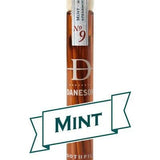 A glass vial labeled “Daneson Toothpick | Mint No. 09” holds essential oil-infused toothpicks with a cool mint flavor, featuring a "MINT" banner on the front.