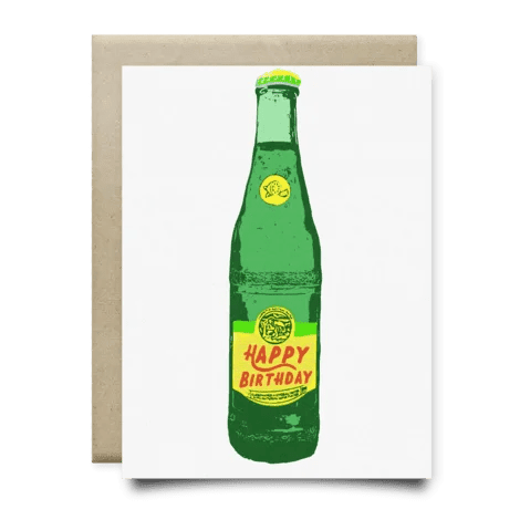 The Topo Happy Birthday Card by Anvil Cards is a blank A2 greeting card featuring a green glass bottle with a yellow "Happy Birthday" label, printed on linen paper, and includes an envelope placed behind the card.