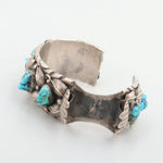 The Vintage Turquoise Watch Cuff is a sterling silver bracelet adorned with multiple turquoise stones, intricate metalwork, elegant leaf motifs, and bead accents.