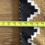 A yellow tape measure on wood measures the width of a Vintage Two Grey Hills Rug by Vintage, showing about 42 cm.