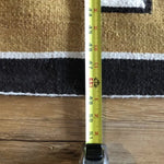 A tape measure shows the Two Grey Hills Rug | Vintage by Vintage in beige and black to be about 48 inches wide, placed on a wooden floor.