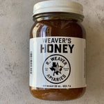 A 22-ounce jar of Weaver's Honey by R. Weaver Apiaries, featuring a white label with the R. Weaver Apiaries logo and text, sits on a light surface—a true taste of Texas honey.