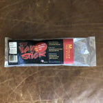 A packaged dog chew labeled "Yak Stick | Rogue Pet Feed" from Rogue Pet Feed sits on a brown leather surface, with packaging highlighting its high protein content and product details.