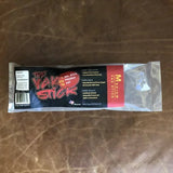 A packaged dog chew labeled "Yak Stick | Rogue Pet Feed" from Rogue Pet Feed sits on a brown leather surface, with packaging highlighting its high protein content and product details.
