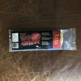 A large Yak Stick dog chew from Rogue Pet Feed, a high-protein treat, is shown on a brown leather surface.