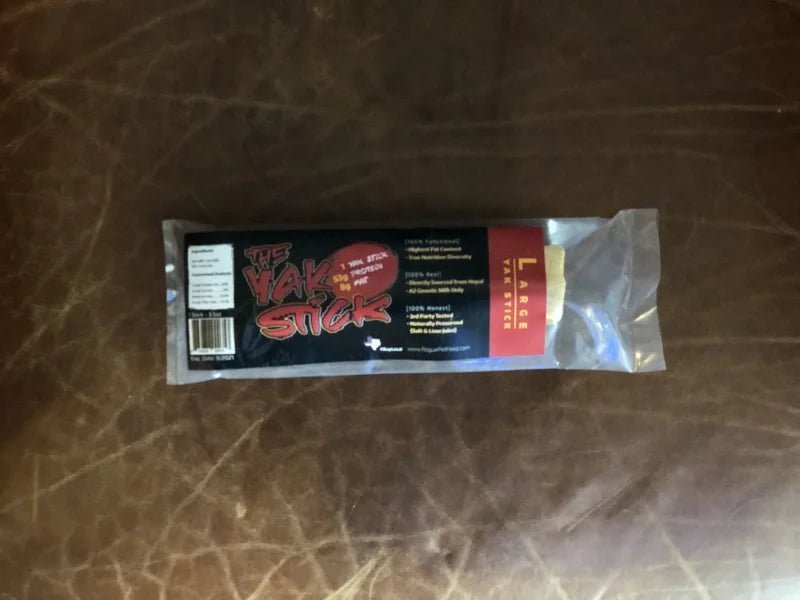 A large Yak Stick dog chew from Rogue Pet Feed, a high-protein treat, is shown on a brown leather surface.