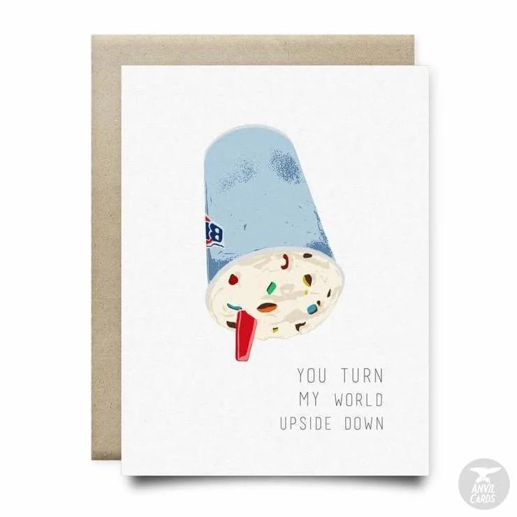 The "You Turn My World Upside Down Card" by Anvil Cards features an illustrated upside-down ice cream cup with candy and the phrase "You turn my world upside down." This A2 linen paper card is blank inside for your own message.